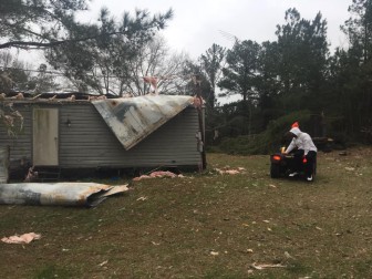 Johnny Washington sits on a four wheeler outside his damaged home. He is about preparing to go around his property to survey damage.