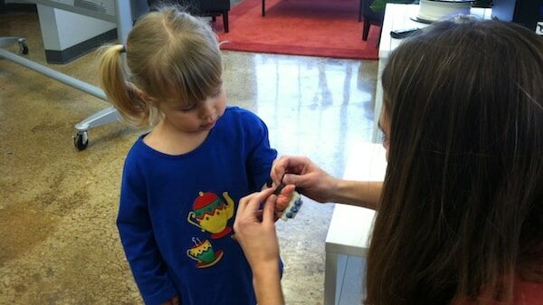 Jessica Berkholtz carefully attaches her daughter Kate's plastic hand.