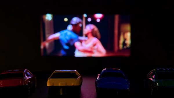 Toy cars in front of a screen mimicking a drive-in theater