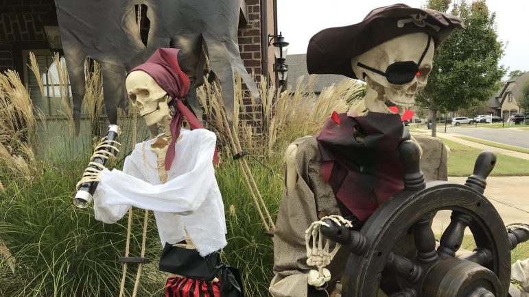 Two plastic skeletons pilot a pirate ship in a Halloween display