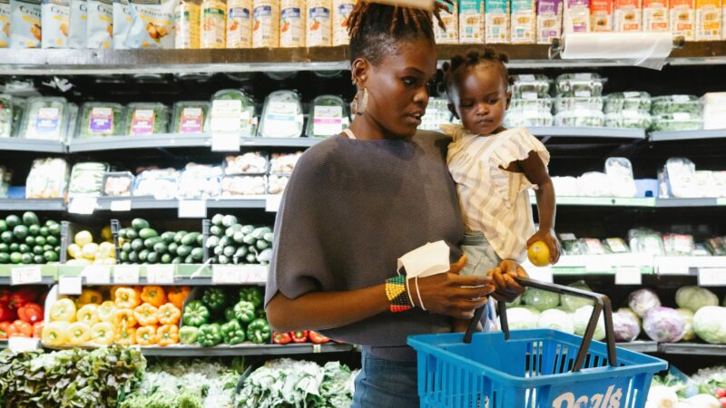 A woman and child grocery shopping in the produce section.