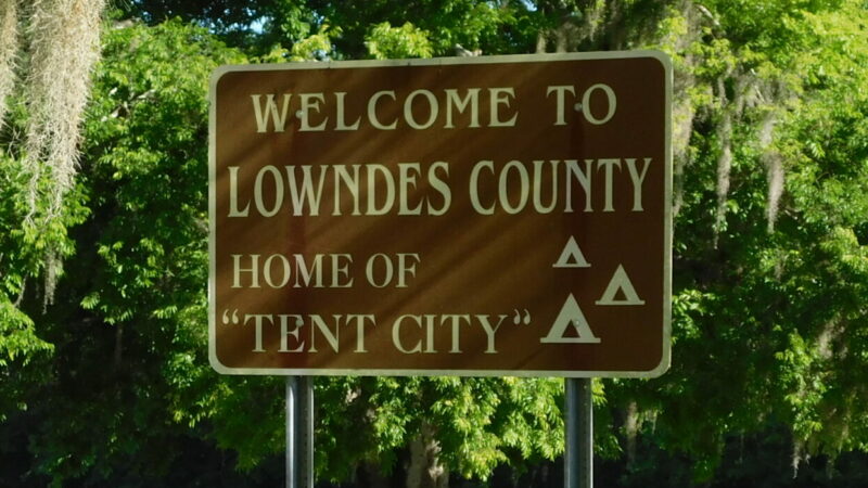 A sign reads "Welcome to Lowndes County. Home of Tent City," in White Hall, Alabama.