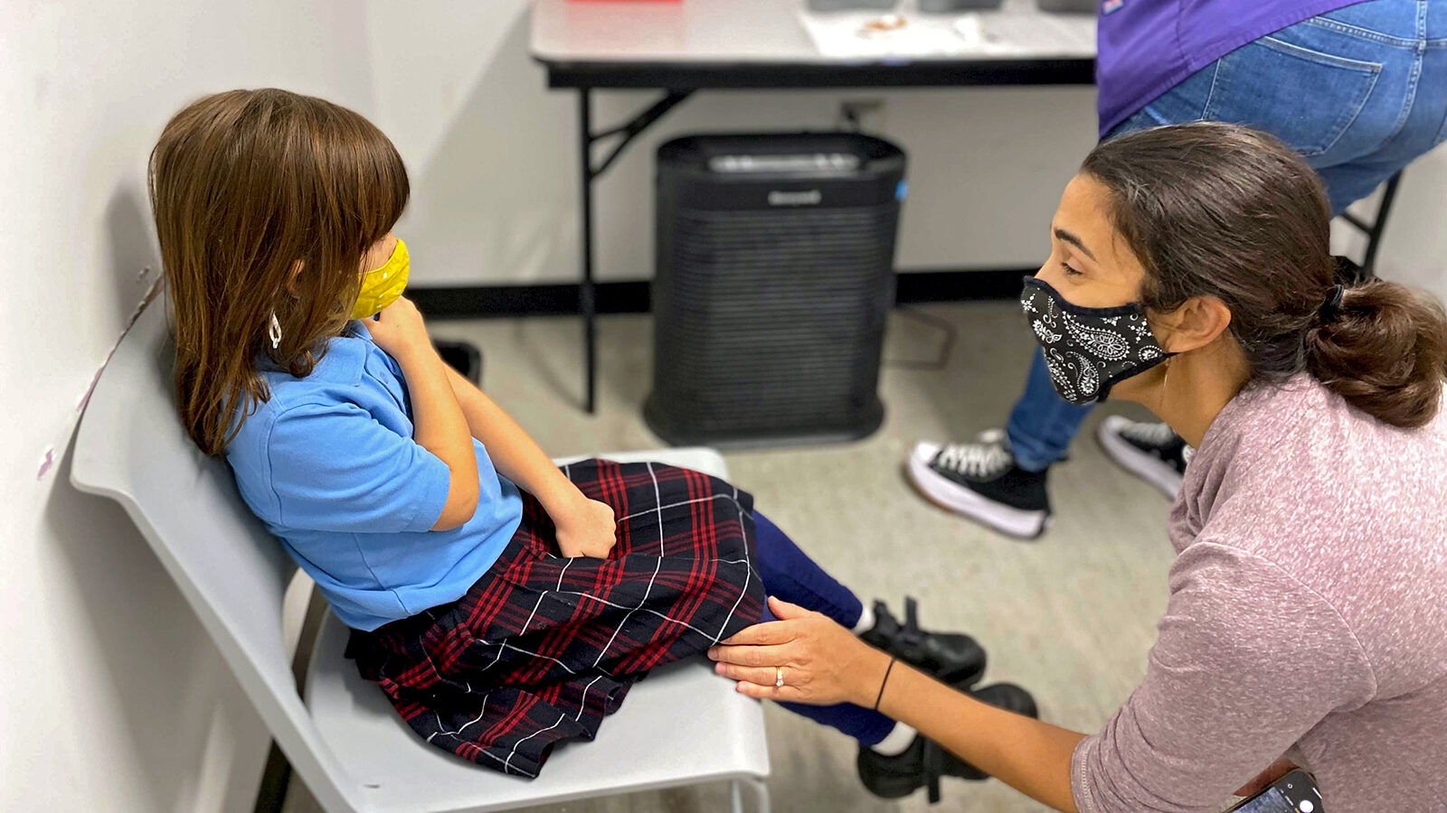 Anjali, 5, rolls up her sleeve in preparation to receiver her COVID-19 vaccine at New Orleans' Crescent Care. Her mother, Priya Lewis, is comforting her before she receives the shot.