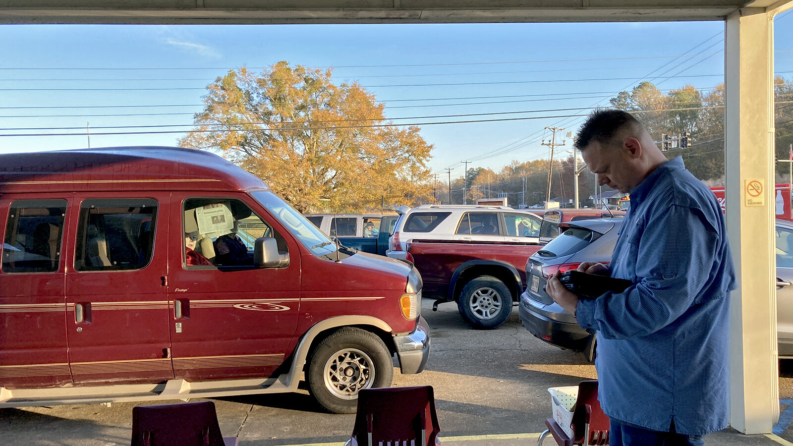 Executive Director Jason Martin oversees the Saint Luke’s Food Pantry car line while a maroon van waits for its turn to receive food and supplies.