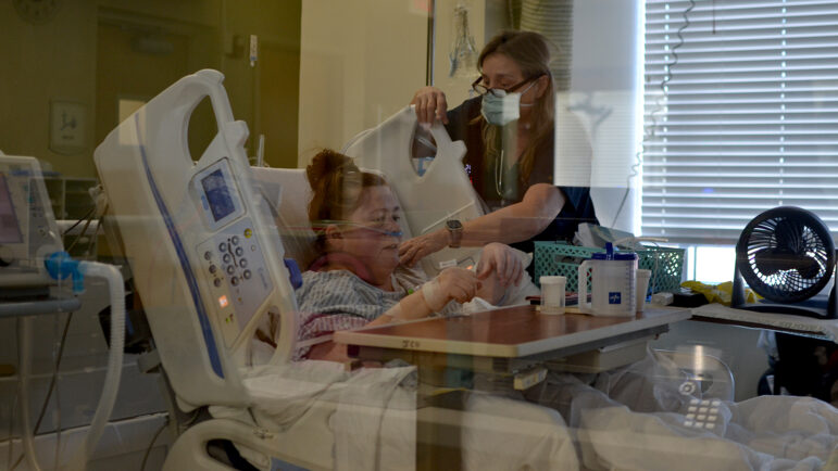 COVID-positive patient Amy Mullins sits up in a hospital bed to receive treatment from a nurse at King's Daughters Medical Center in Brookhaven, Mississippi.