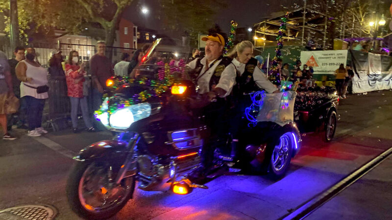 A motorcycle drives down the street in Uptown New Orleans with the Krewe Of Nyx.
