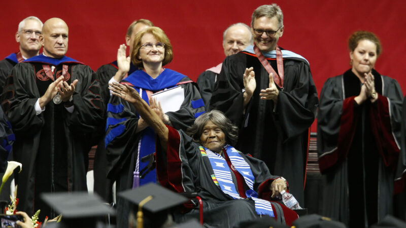 Autherine Lucy Foster, center, the first black student to attend the University of Alabama, waves as the university awarded her an honorary doctorate during a commencement ceremony, on,May 3, 2019, in Tuscaloosa, Ala. The University of Alabama is reconsidering its decision last week to retain the name of a one-time governor who led the Ku Klux Klan on a campus building while adding the name of the school's first Black student. Trustees will meet publicly in a livestreamed video conference on Friday, Feb. 11, 202, to revisit their decision to keep the name of former Alabama Gov. Bibb Graves on a three-story hall while renaming it Lucy-Graves Hall to also honor Autherine Lucy Foster, the University of Alabama System said. ( Gary Cosby Jr./The Tuscaloosa News via AP)