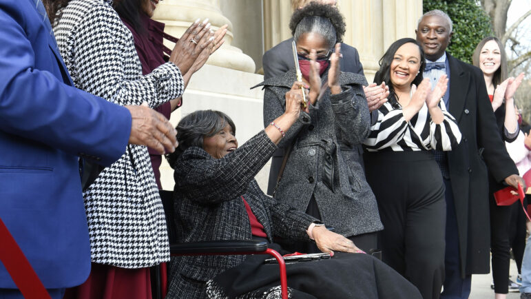 Autherine Lucy Foster lifts the scissors in celebration after cutting the ribbon during a renaming ceremony for Autherine Lucy Foster Hall in Tuscaloosa, Ala., on Friday, Feb. 25, 2022. The building was dedicated in honor of Lucy, the first Black student to enroll at the university. (Gary Cosby Jr./The Tuscaloosa News via AP)