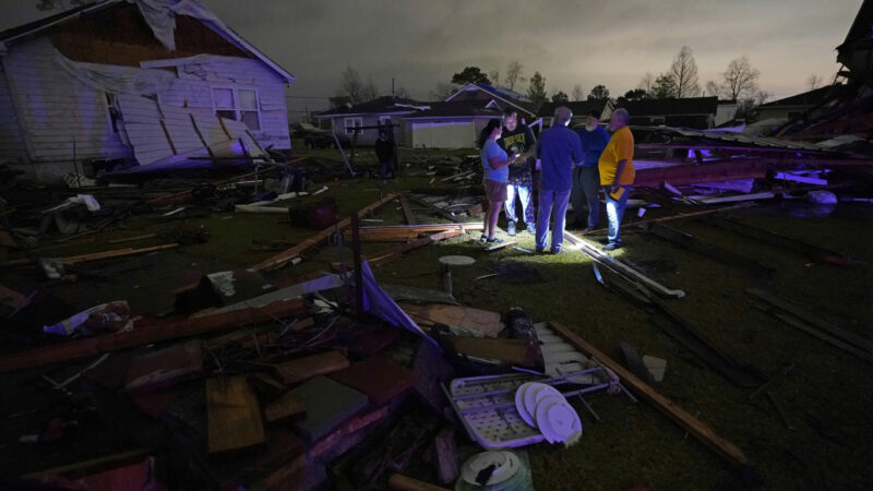 Christine Wiecek, left, and her husband Robert Patchus, second left, talk to neighbors amongst debris of their damaged homes after a tornado struck the area in Arabi, La., Tuesday, March 22, 2022. A tornado tore through parts of New Orleans and its suburbs Tuesday night, ripping down power lines and scattering debris in a part of the city that had been heavily damaged by Hurricane Katrina 17 years ago. (AP Photo/Gerald Herbert)