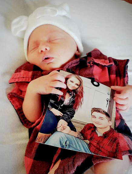 8-month-old Khaleesi Kendrick holds a photo of her parents.