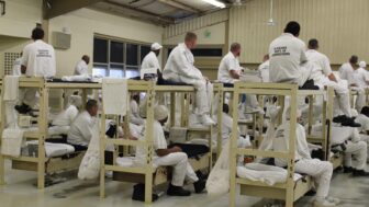 Men sit on their bunks in a dormitory at Alabama’s Bibb County Correctional Facility, March 13, 2020.
