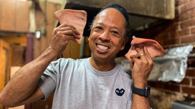 Geno Lee, fourth generation owner of the Big Apple Inn, holds up two tasty pig ears.