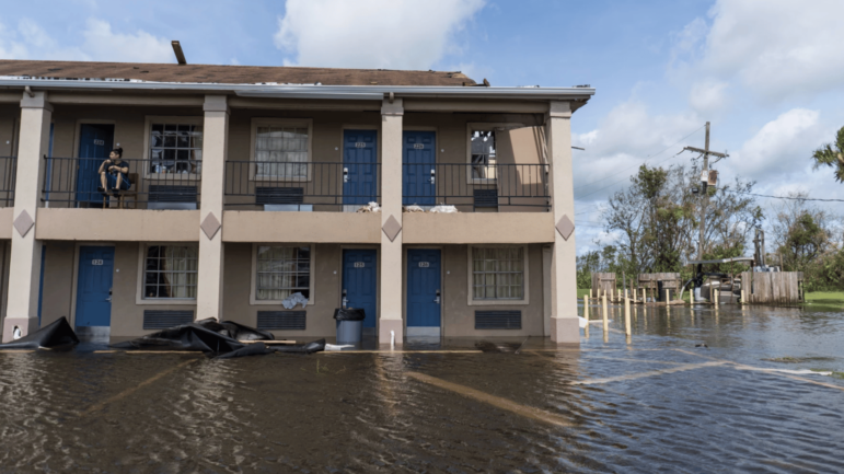 In this file photo, a woman sits on a balcony at the Lake Houmas Inn after the roof caved in and floodwaters cover the parking lot in Houma, Louisiana following Hurricane Ida, Aug. 30, 2021.