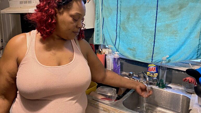 In this file photo, South Jackson resident Baylis McDaniels runs water from the tap in her home, Feb. 2021.