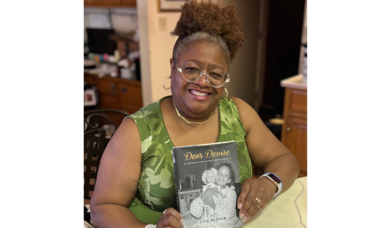Lisa McNair holding her book that pictures her sister, Denise.
