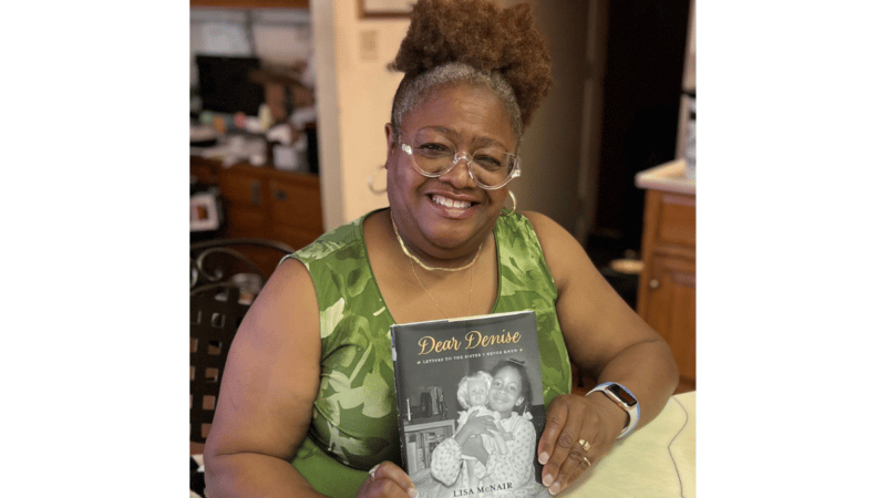 Lisa McNair holding her book that pictures her sister, Denise.