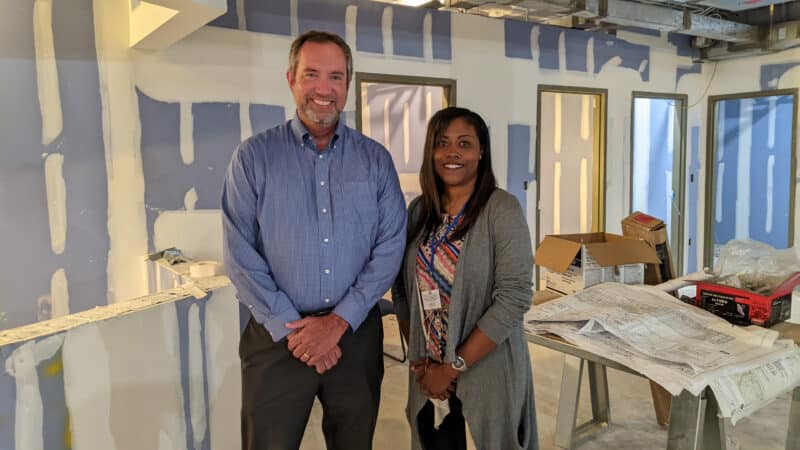 Man and woman stand in a room that is under construction.