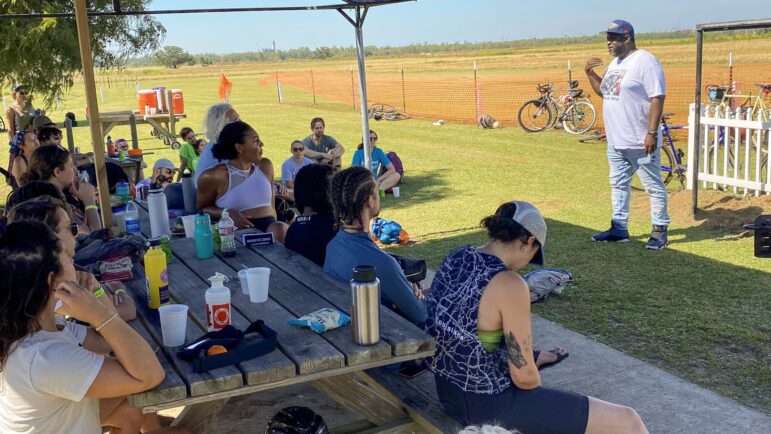 Cyclists listen to Everett Offray, who was formerly incarcerated, speak about his experience in prison and his work in helping secure the release of other incarcerated people during the NOLA to Angola bike ride, Oct. 15, 2022.