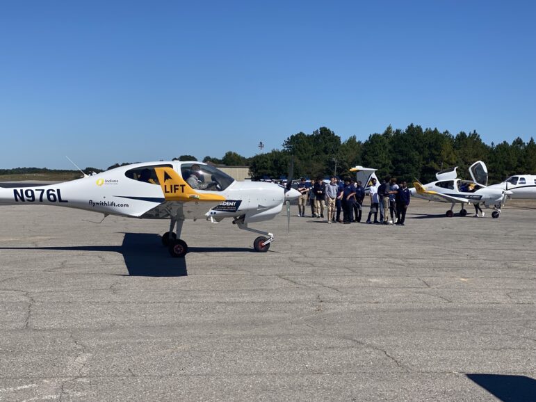 Students line up in front of a small plane