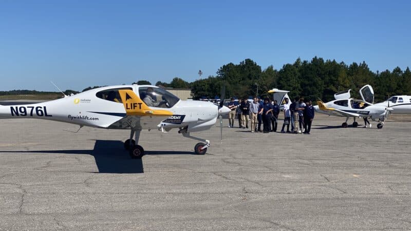 Students line up in front of a small plane