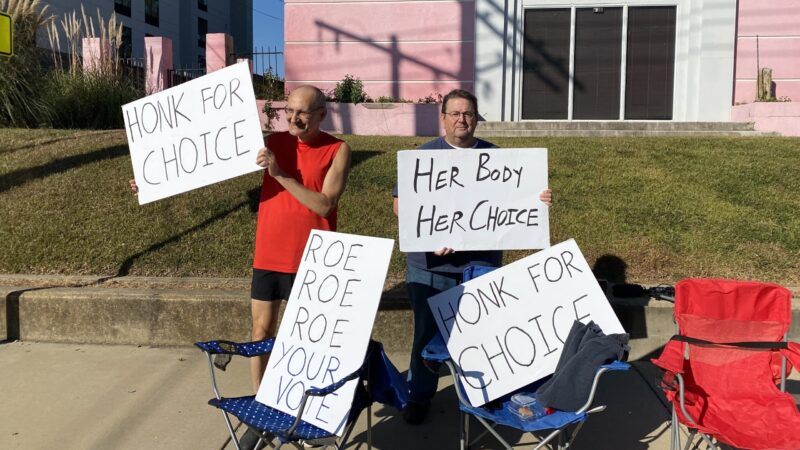 John Osborne (left) and Philip Harizi (right) stand outside the closed Jackson Women's Health Organization clinic in Jackson, Mississippi. The two are holding signs that read "Honk for choice," "Her body her choice" and "Roe Roe Roe your vote."