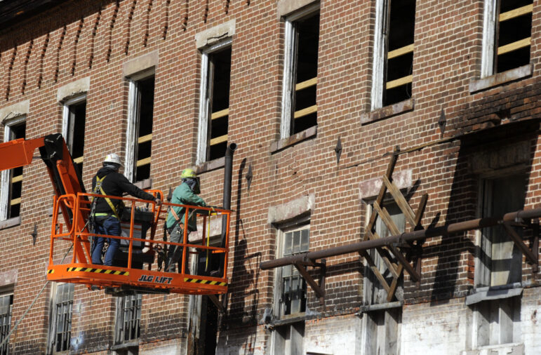 Construction crew members on a lift work on a once-abandoned cotton gin factory that is being renovated into apartments in Prattville, Ala.