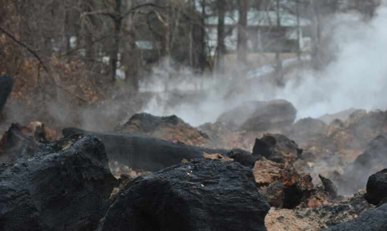 Smoke and dirt surround smoldering pieces of wood at the landfill in Moody, Alabama.