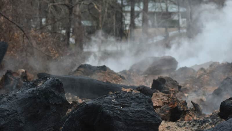 Smoke and dirt surround smoldering pieces of wood at the landfill in Moody, Alabama.