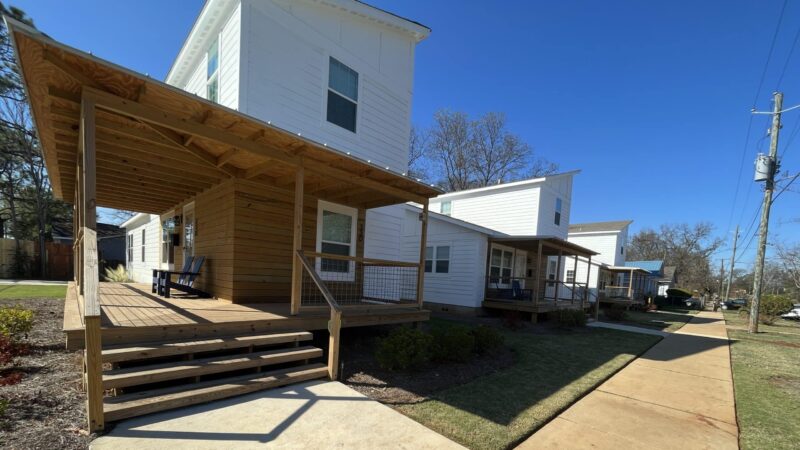A white modular home with a front porch in Titusville's "Live on 1st" stands near a sidewalk.
