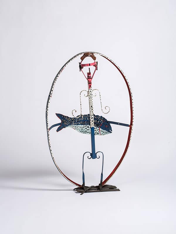 Thornton Dial's Man with His Bream is a circular metal sculpture with a blue painted fish displayed in the center.