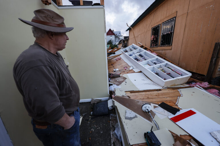 A man looks at a damaged business after a tornado.
