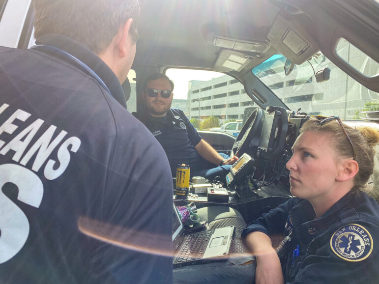 Ambulance crew members stand in the door of a vehicle.