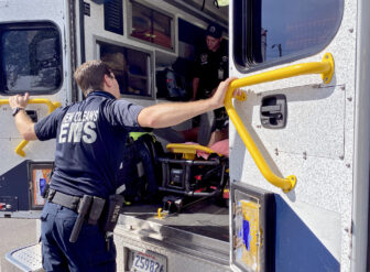 A man in an EMS uniform loads a gurney into an ambulance.