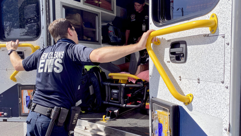 A man in an EMS uniform loads a gurney into an ambulance.
