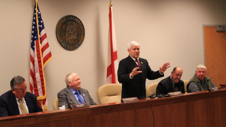 St. Clair County Commission Chairman Stan Bateman stands between the county's four commissioners, and talks to an audience at an open meeting.