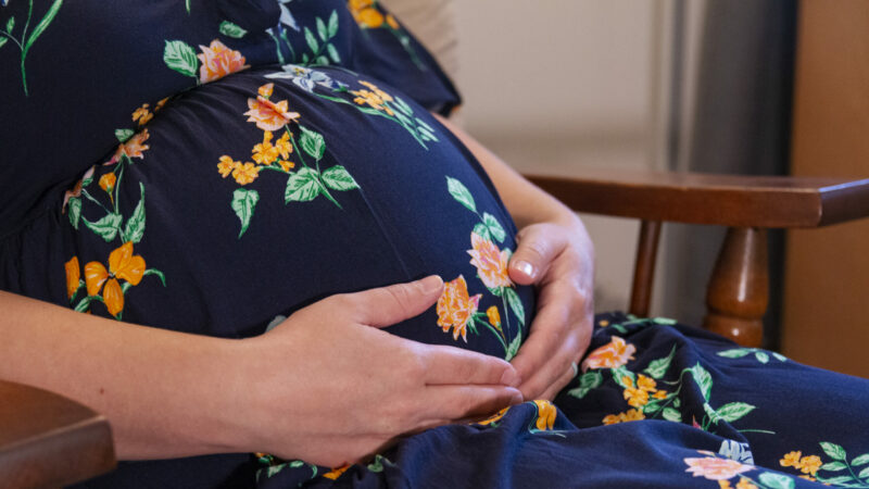 A stock image of a pregnant woman holding her stomach.