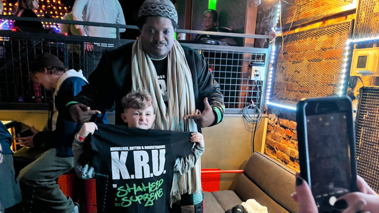 A boy holds a K.R.U. shirt