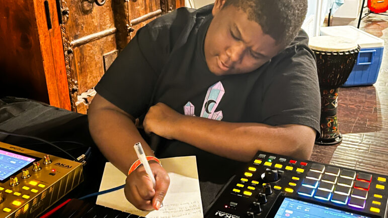 A boy writes a rap song on a desk