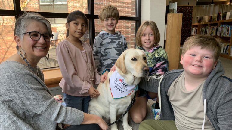 Librarian Fran Woodruff and Foxie sit with students Kaylie Cruz, Camp Hess, Rosie Cooper, and Gavin Martinson.