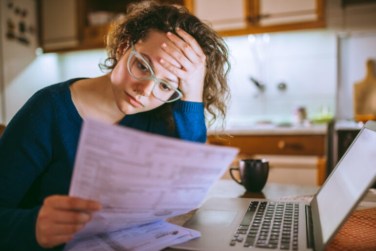 Young brunette curly female reading her tax papers, looking stressed.