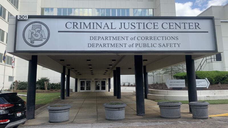 A sign outside a government building reads: Criminal Justice Center: Department of Corrections. Department of Public Safety.