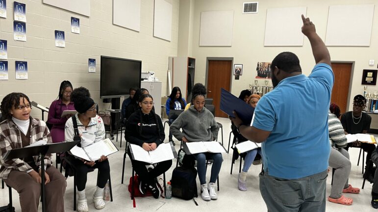 A choir director leads students in rehearsal