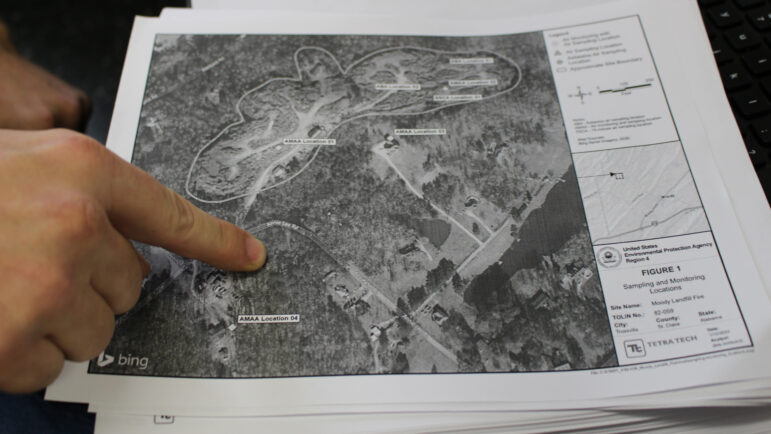 A hand points to a spot on a map showing the Environmental Landfill, Inc. site.