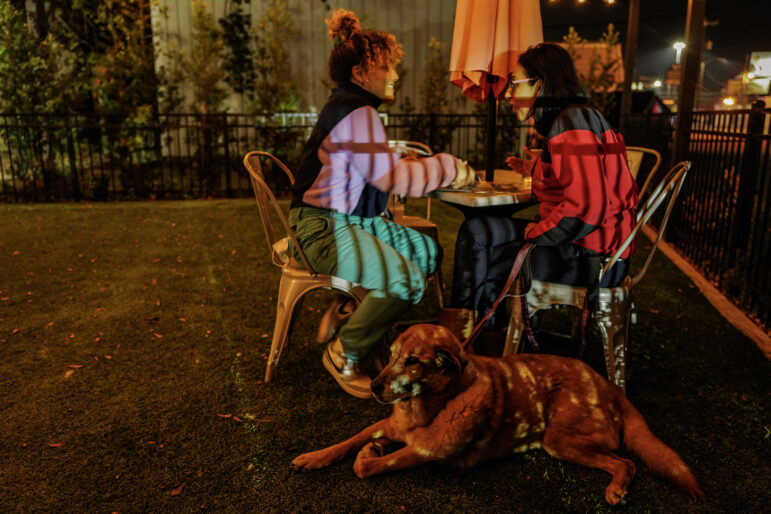 Tania Wolf and Nora Ahmed decompress while Ahmed’s dog, Orion, rests at their feet at a restaurant in Alexandria, Louisiana. The two spent the day visiting detainees at South Louisiana ICE Processing Center, a women’s immigration detention facility in Basile, Louisiana.