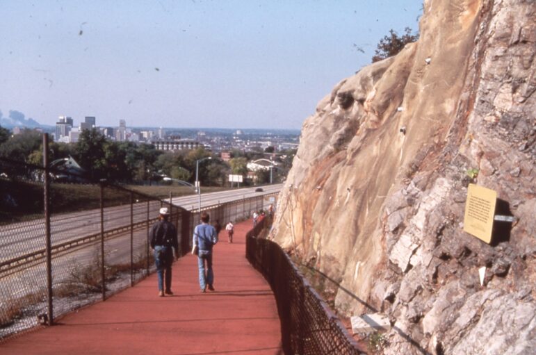 Image shows a walkway above highway 280, which follows along the inner wall of the red mountain cut.