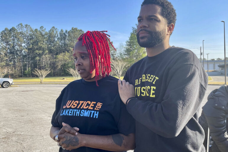 A man comforts a woman in a shirt that reads "Justice for Lakeith Smith."