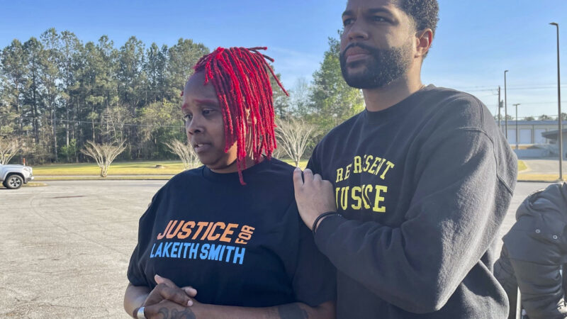 A man comforts a woman in a shirt that reads "Justice for Lakeith Smith."