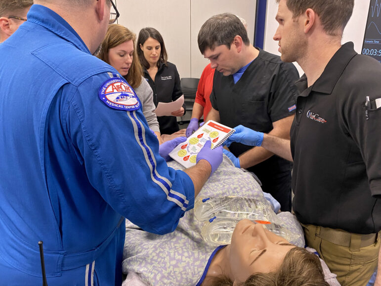 The team leading Victoria’s care at a STORK training simulation at UMMC consult the manual, found in their STORK bag, to determine how to stop a postpartum hemorrhage, Feb. 16, 2023.