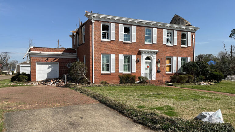 A two-story brick home has no roof and is missing windows.