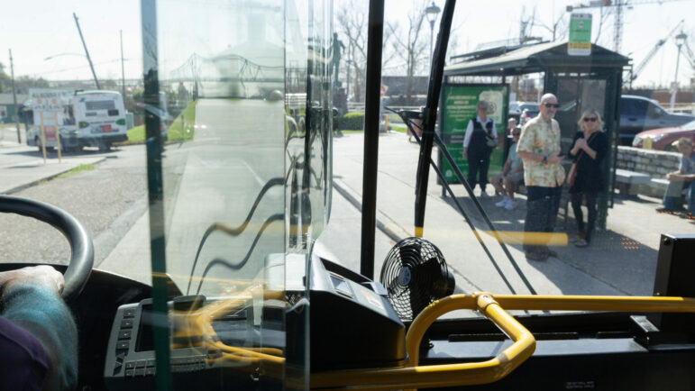 A bus pulls up to the Canal Street Ferry bus stop where riders wait to cross the Mississippi River on Jan. 19, 2023, in New Orleans, Louisiana. The ferry wasn’t operational, so waiting riders instead took a bus across the Crescent City Connection to get over the river.